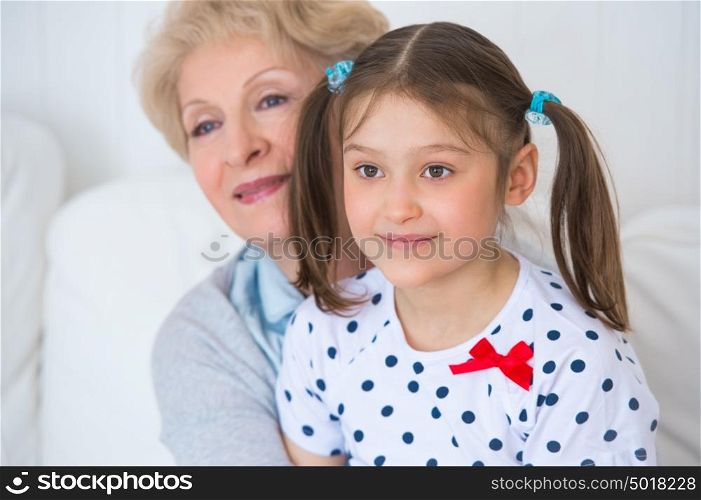 Lovely little girl with her grandmother having fun and happy moments together at home