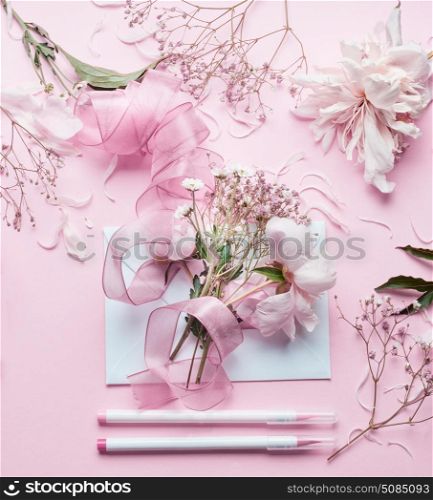 Lovely pink Florist workspace. Beautiful flowers, envelop ,ribbon and markers pencil on pastel background, top view. Creative Invitation and holiday concept