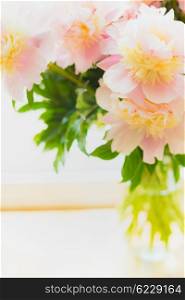 Lovely pink pale peonies in glass vase on light background, close up