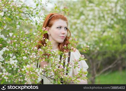 lovely red-haired girl walks in apple orchard