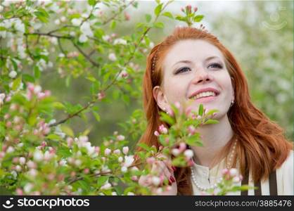 lovely red-haired girl walks in apple orchard
