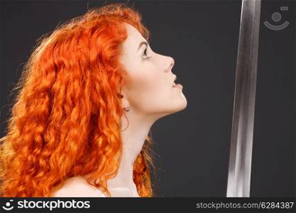lovely redhead with medieval sword over grey