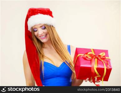 Lovely smiling woman wearing santa claus hat holding big red christmas present gift. Xmas, happiness, winter and people concept. Woman in santa claus hat holds gift box. Christmas time