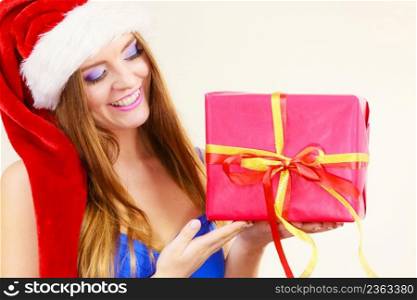 Lovely smiling woman wearing santa claus hat holding big red christmas present gift. Xmas, happiness, winter and people concept. Woman in santa claus hat holds gift box. Christmas time