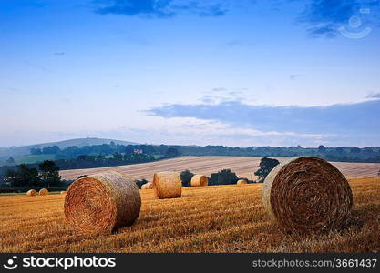 Lovely sunset golden hour landscape of hay bales in field in English countryside