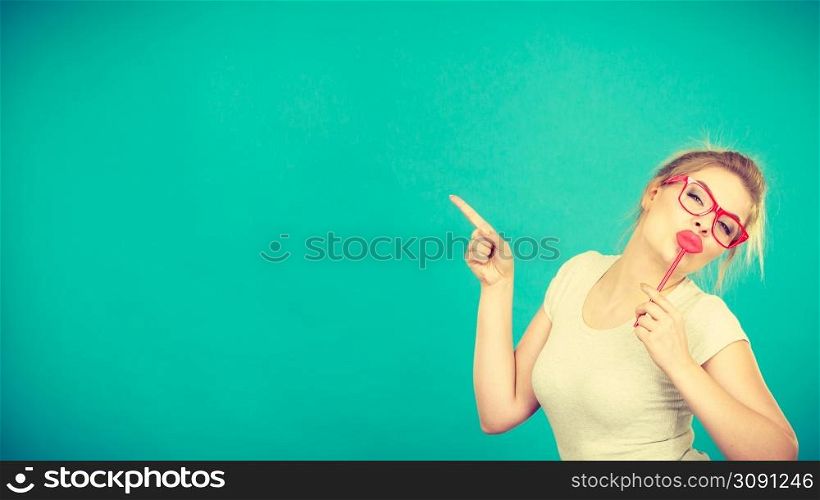 Lovely sweet woman casual style nerdy glasses holding red fake lips on stick having fun, on green blue. Photo take and carnival funny accessories concept.. Happy woman holding fake lips on stick
