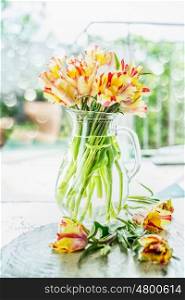 Lovely tulips bunch in glass vase with water on table at spring day background, front view