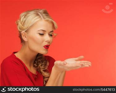 lovely woman in red dress blowing something on the palms of her hands