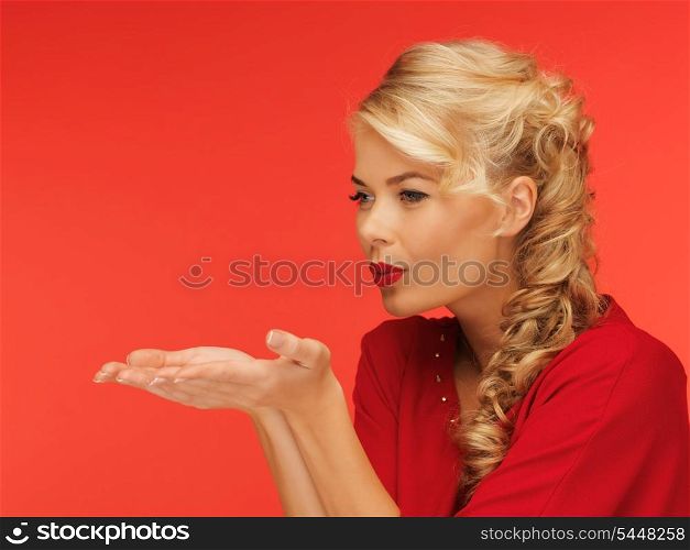 lovely woman in red dress blowing something on the palms of her hands