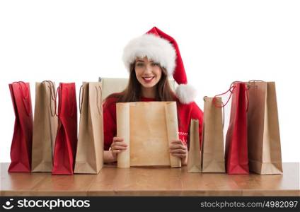 Lovely woman with shopping bags wearing Santa Claus hat dreaming and holding copyspace