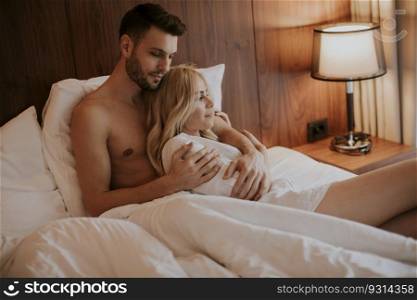 Lovely young couple hugging on their bed at home