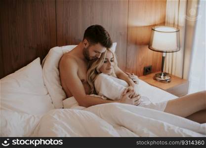 Lovely young couple hugging on their bed at home
