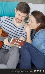 lovely young couple playing guitar at home