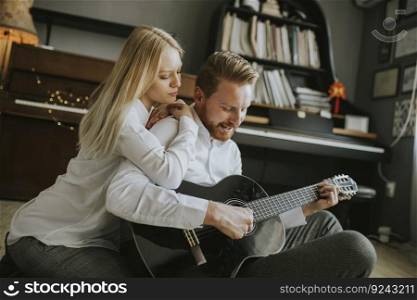 Lovely young couple playing guitar in the room