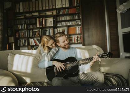 Lovely young couple playing guitar in the room