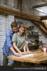 Lovely young couple preparing dough at home in the rustic kitchen