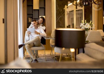 Lovely young couple relaxing at luxurious home with digital tablet