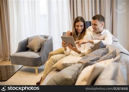 Lovely young couple relaxing at luxurious home with digital tablet
