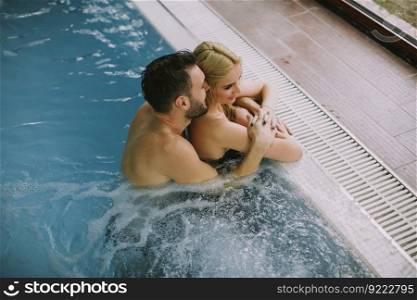 Lovely young couple relaxing on the poolside of interior swimming pool