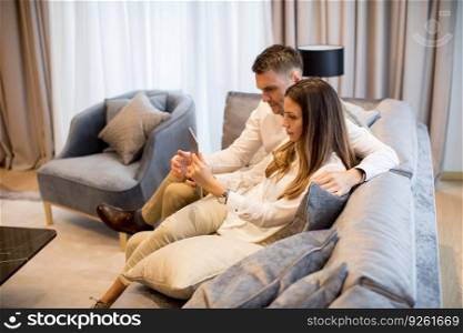 Lovely young couple with digital tablet in the room of an contemporary apartment