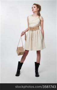 Lovely young female in modern dress with handbag posing in studio. Series of fashion photos