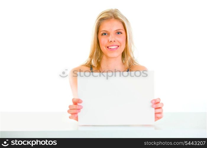 Lovely young girl sitting at table and holding blank paper&#xA;