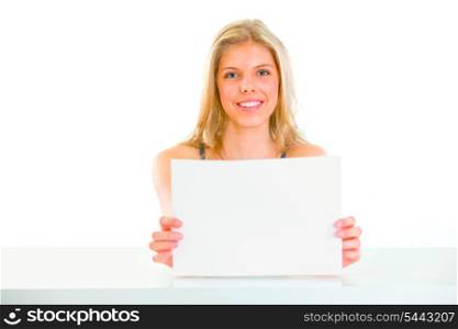 Lovely young girl sitting at table and holding blank paper&#xA;