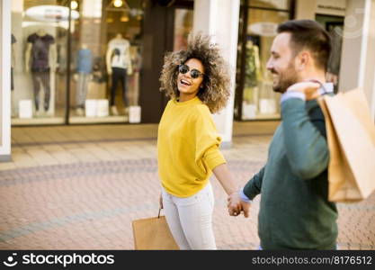 Lovely young multiethnic couple with bags in the shopping