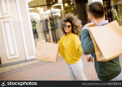 Lovely young multiethnic couple with bags in the shopping