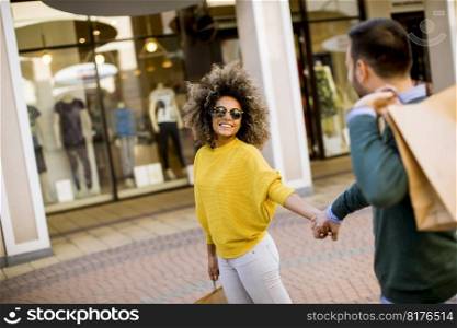 Lovely young multiethnic couple with bags in the shopping