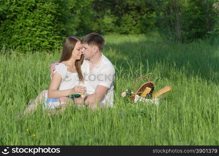 Lovers girl and boy hugging on the grass during a picnic in a city park