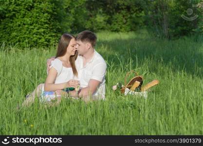 Lovers girl and boy hugging on the grass during a picnic in a city park