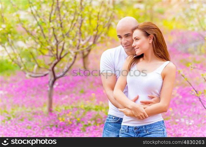 Lovers hugging outdoors in springtime, spending time on backyard, pink floral meadow, enjoying family, love concept