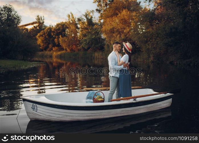 Lovers hugs in a boat on quiet lake at summer day. Romantic meeting, boating trip, man and woman walking along the river. Lovers hugs in a boat on quiet lake at summer day