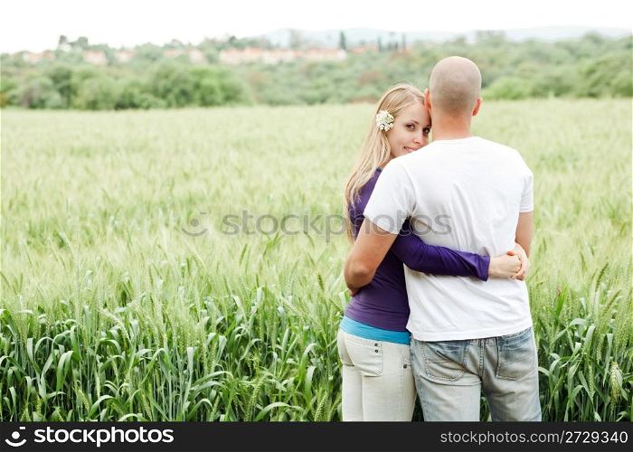 Lovers in park rear view, woman looking at camera in park