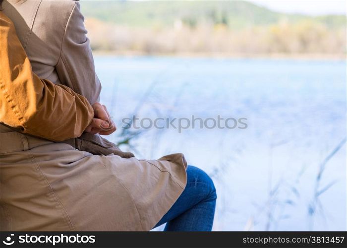 Lovers sitting in front of a lake in autumn