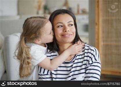 Loving adopted daughter hugs, kissing foster mother or babysitter, little elementary kid girl embracing smiling mom. Happy motherhood, warm relationship, custody of child, adoption concept.. Loving adopted daughter hugs, kissing foster mom. Happy motherhood, custody of child girl, adoption