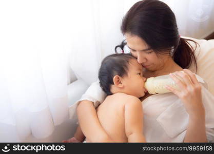 Loving and affectionate mother holding newborn baby indoors at home.. Side view of loving mother with newborn baby indoors at home.