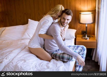 Loving and hugged young couple sitting on the bed in the bedroom