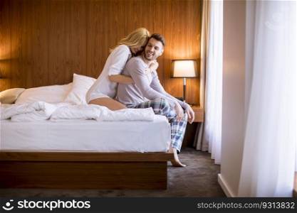 Loving and hugged young couple sitting on the bed in the bedroom