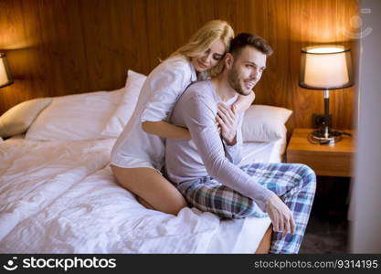 Loving and hugged young couple sitting on the bed in the bedroom