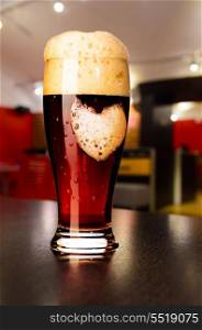 loving beer. glass of fresh draft dark beer on table in pub. loving beer