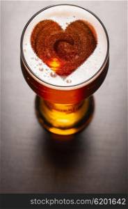 loving beer, heart symbol on foam in glass on black table, view from above