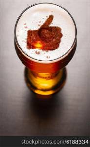 loving beer, thumb symbol on foam in glass on black table, view from above