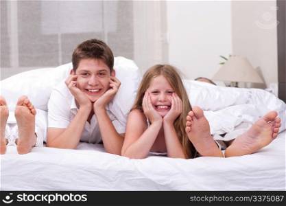 Loving Brother and sister lying and having fun on the bed looking at you
