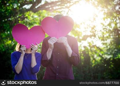 Loving couple. Beautiful young loving couple holding paper hearts and smiling in outdoor nature vintage tone, valentine concept.