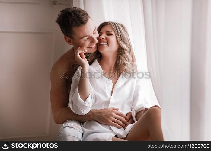loving couple having fun together at home, playful wife biting smiling husband ear, piggyback, man and woman playing childish in bed, enjoying funny intimate moments