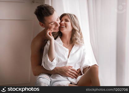 loving couple having fun together at home, playful wife biting smiling husband ear, piggyback, man and woman playing childish in bed, enjoying funny intimate moments