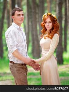 Loving couple in the forest, young lovers holding hands and posing, fashion look on happy wedding day, love and tenderness in relationship