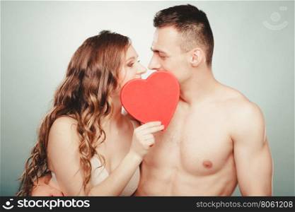 Loving couple kissing behind red heart. Love.. Happy loving young couple kissing behind red heart. Nude naked man and woman with symbol sign of love. Relationship closeness.